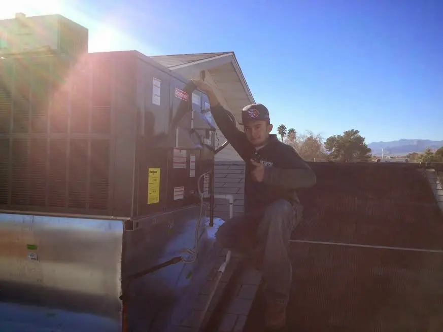 HVAC technician performing AC Tune-Up on a rooftop unit in Calimesa